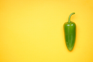 Jalapeno pepper on a yellow background, place for text. Green chili pepper. Top view.