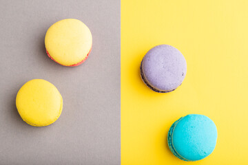 Fototapeta premium Yellow, purple and blue macaroons on trendy gray and yellow background. top view, copy space.