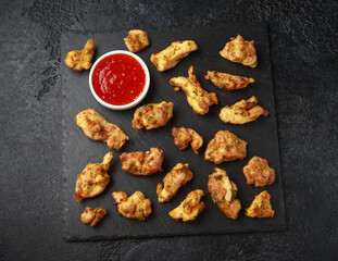 Chicken Pakora dish with sweet chilli sauce on rustic stone board