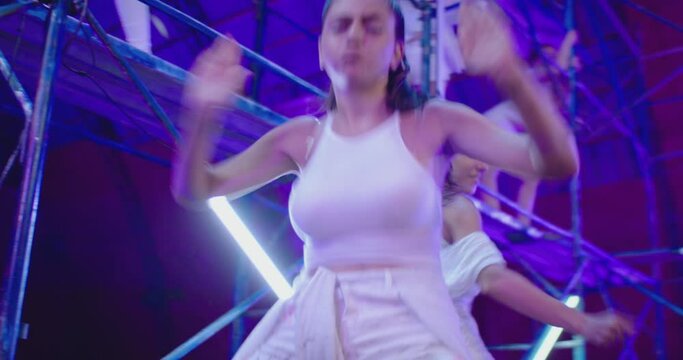 Many female dancers dressed in white shorts dancing inside abandoned building in high multistage  construction . Stylish Girls dancing, twerking , doing gymnastic movements , jumping . 