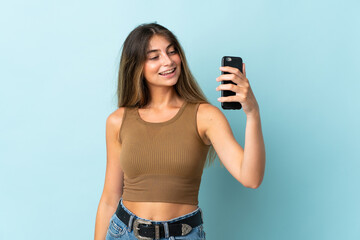 Young caucasian woman isolated on blue background making a selfie