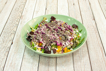 corn salad with yogurt are wheat seeds and purple cabbage on a green deep plate
