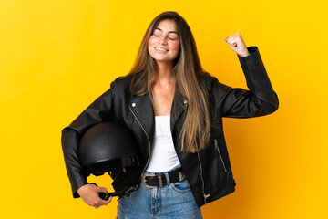 Woman holding a motorcycle helmet isolated on yellow background doing strong gesture