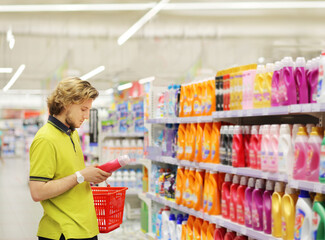 Man shopping in supermarket reading product information.(diapers,detergent)