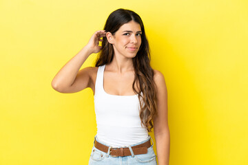 Young caucasian woman isolated on yellow background having doubts