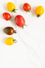 red and yellow colored tomatoes on a marble surface. flat lay, top view
