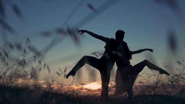 Aerial: Male and female ballet dancer embracing at sunset in silhouette