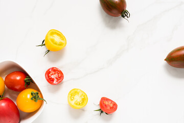 Naklejka na ściany i meble red and yellow colored tomatoes on a marble surface. flat lay, top view