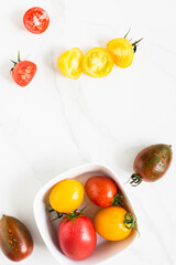 red and yellow colored tomatoes on a marble surface. flat lay, top view