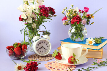 Obraz na płótnie Canvas The concept of good morning and good mood. Books, a cup of tea, wild flowers in vases, strawberries in and around a glass cup, a clock on a light background