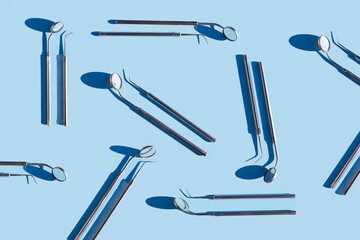 set of medical dental tool, equipment, pattern with hard shadows on blue background. mirror and probe for treatment, hygiene, examination of  oral cavity.