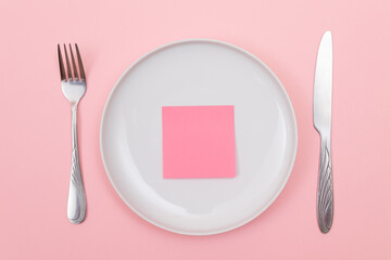 Colored Sticky Note or Memo Paper on White Ceramic Plate Lying On Pink Background - Top View, Flat Lay