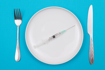 Medical Disposable Syringe on White Ceramic Plate Lying On Blue Background - Top View, Flat Lay