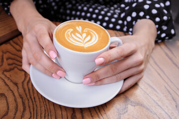 Woman with manicure holding cup of coffee. Top view. Outside.