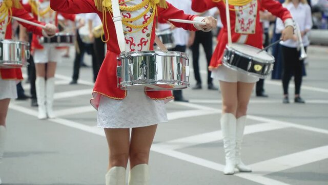 Street performance of festive march of drummers girls in red costumes on city street. Young girls drummer in red vintage uniform at the parade
