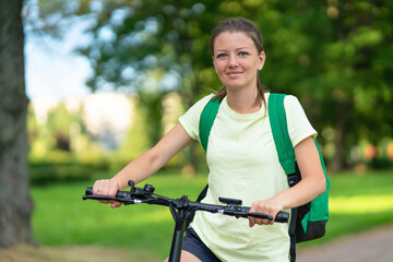 Obraz premium portrait happy beautiful girl traveling on electric bike, active young woman riding bicycle, female biking in park, nature at summer. travel, healthy lifestyle, sport concept. closeup