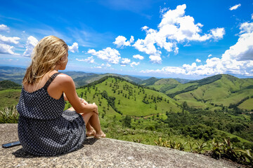 Mulher olhando a paisagem em cima de uma pedra.
