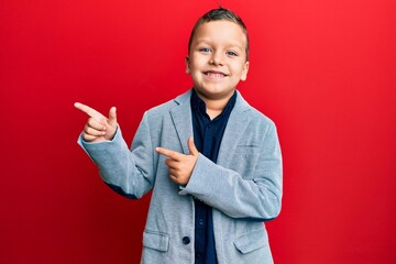 Little kid boy wearing elegant business jacket smiling and looking at the camera pointing with two hands and fingers to the side.