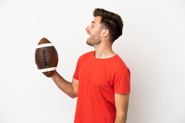 Young caucasian man playing rugby isolated on white background laughing in lateral position
