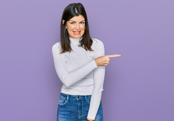 Beautiful brunette woman wearing casual clothes pointing aside worried and nervous with forefinger,...
