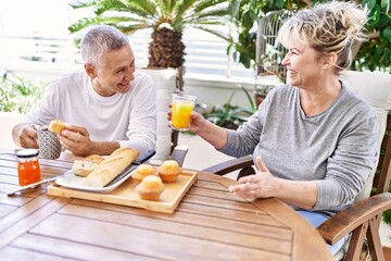 Senior caucasian couple smiling happy having breakfast at the terrace.