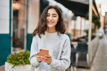 Young middle east girl smiling happy using smartphone at the city.