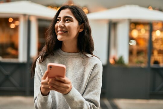 Young middle east girl smiling happy using smartphone at the city.