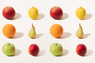 Arranged red apple, orange, green apple, yellow lemon, yellow pear and red peach on a light background. Summer and winter fruit season. Minimal pattern.