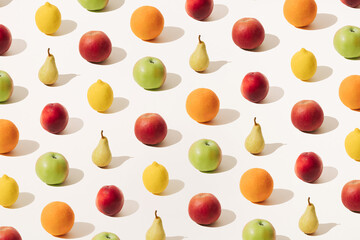 Arranged red apple, orange, green apple, yellow lemon, yellow pear and red peach on a light background. Summer and winter fruit season. Minimal pattern.