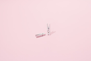 Two white clips on a pink background. One stands and the other is laid. Minimal design.