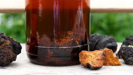 Superfood trendy organic Chaga mushroom and chaga mushroom tea in a glass jar with pieces of...
