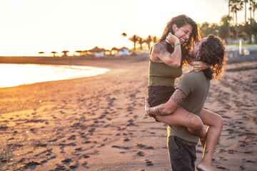 Beautiful lovely young couple on the beach during sunset having fun together, laughing. Real people...