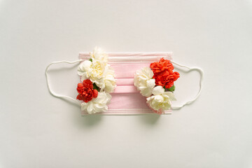 Arrangement of beautiful, fresh white and red daisy flowers and pink face mask. Flat lay.