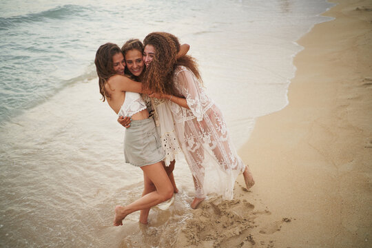 Three Sisters Hugging Each Other Happily At Beach