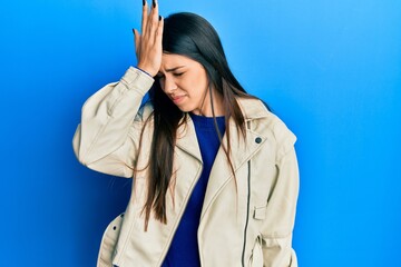 Young hispanic woman wearing casual leather jacket surprised with hand on head for mistake,...