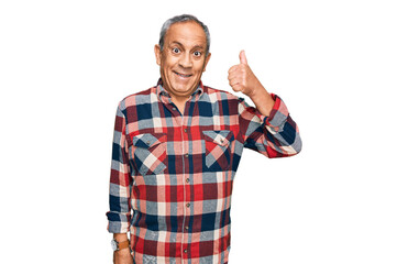 Senior hispanic man wearing casual clothes smiling happy and positive, thumb up doing excellent and approval sign