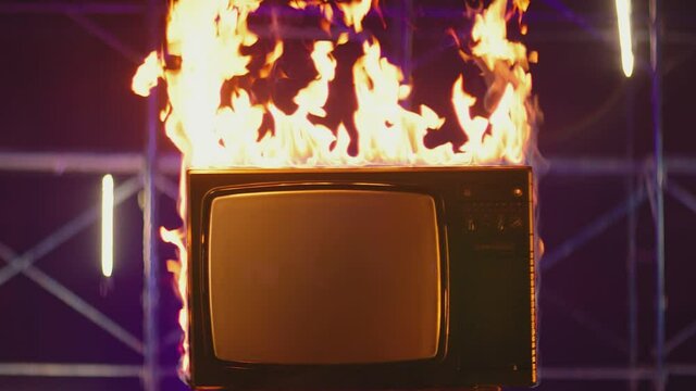 Old TV Set with big Screen in Fire . Old TVs burning on fire . Concept of modern technology , internet and anti-propaganda . Destruction of retro TV. 80s or 90s TV set blazing in slow motion
