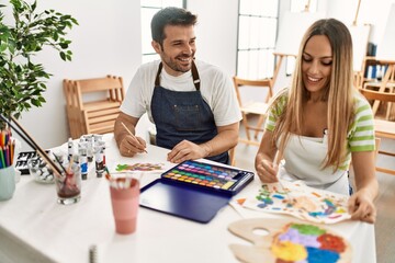 Fototapeta premium Two students smiling happy painting sitting on the table at art school.