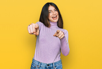 Young beautiful teen girl wearing turtleneck sweater pointing to you and the camera with fingers, smiling positive and cheerful