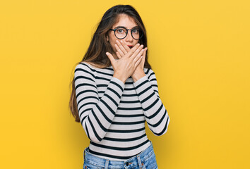 Young beautiful teen girl wearing casual clothes and glasses shocked covering mouth with hands for mistake. secret concept.