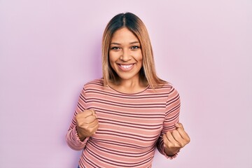 Obraz premium Beautiful hispanic woman wearing casual striped sweater excited for success with arms raised and eyes closed celebrating victory smiling. winner concept.
