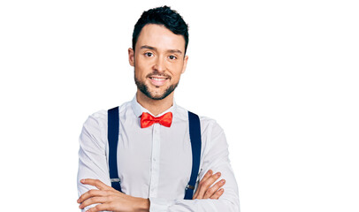 Hispanic man with beard wearing hipster look with bow tie and suspenders happy face smiling with...