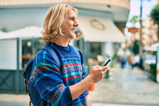 Young scandinavian student man smiling happy using smartphone at the city.