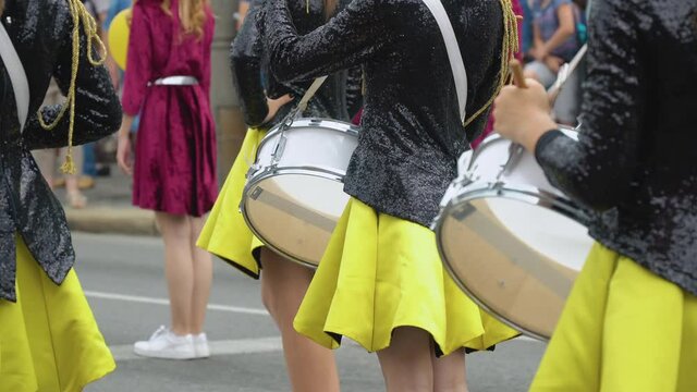 Close-up of hands of female drummers in yellow black vintage uniform at parade. Street performance. Parade of majorettes