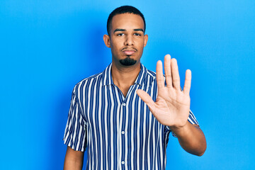 Young african american man wearing casual clothes doing stop sing with palm of the hand. warning...