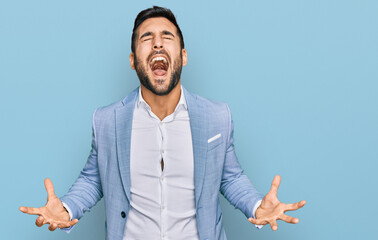 Young hispanic man wearing business jacket crazy and mad shouting and yelling with aggressive...