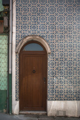 The door to the traditional Portuguese building. Old tiles wall on the street painted tin-glazed, azulejos.