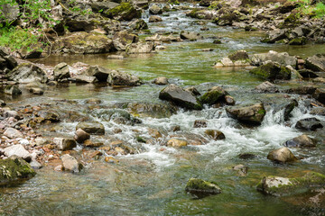 Closeup image of the flow of a river filled with wet stones