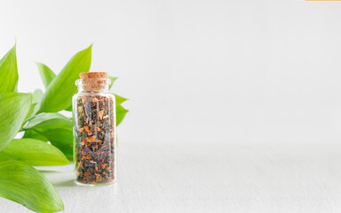 A bottle of medicinal herb next to a green branch