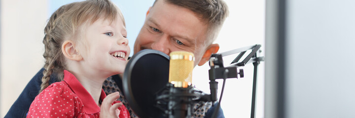 Man and girl are recording their voice on microphone